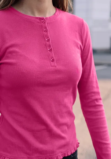 Roze longsleeve met knoopsluiting aan de ronde hals en een subtiel gerimpelde zoom.