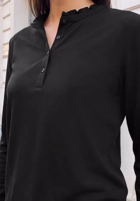 Schwarzlangärmeliges Henley-Shirt mit Rüschenkragen, Knopfleiste und schmaler Passform vor hellem Hintergrund.