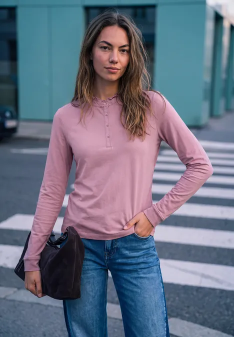 Langarm Shirt mit Rundhals und Rüschen pearly rose Junge Frau in rosa Langarmshirt und Jeans steht lässig auf dem Zebrastreifen, hält eine Tasche.