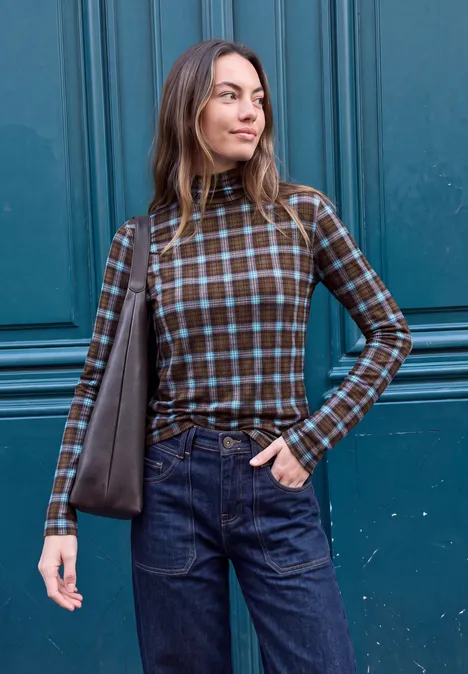 T-shirt à manches longues, col roulé et imprimé loom blue Eine Frau trägt ein kariertes Langarmshirt, Jeans und eine Schultertasche vor einer blauen Holztür.