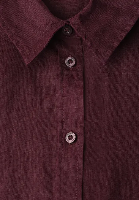 Zbliżenie bordowej lnianej koszuli z kołnierzem i plisą na guziki.