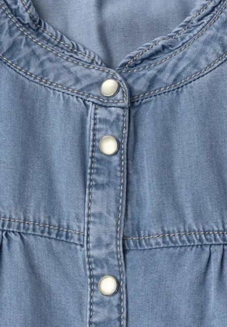 Nahe Aufnahme eines hellblauen Jeanskleids mit weißen Druckknöpfen