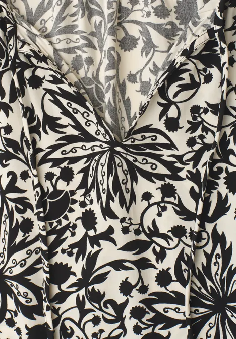 Witte stof met zwart barok bloemen- en bladmotief in V-vorm.