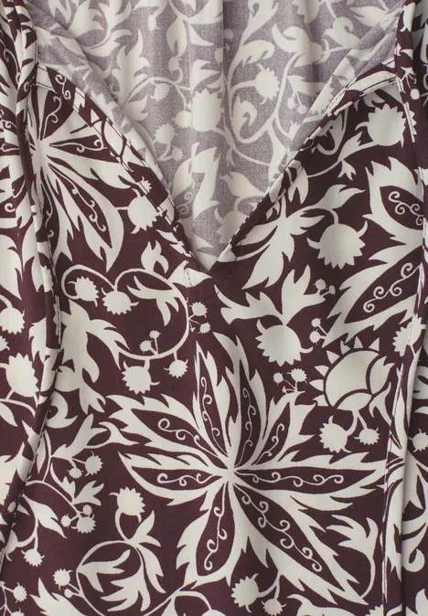 Nahaufnahme eines braun-beigen Stoffes mit symmetrischem Blumen- und Blattmuster.