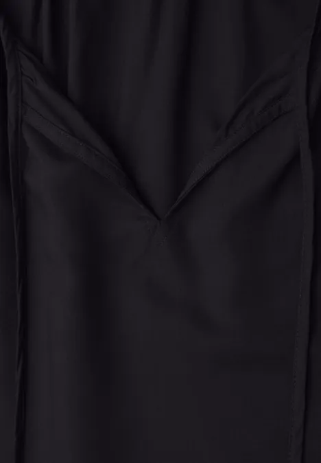 Nahaufnahme eines schwarzen Stoffes mit gefaltetem V-förmigen Muster.