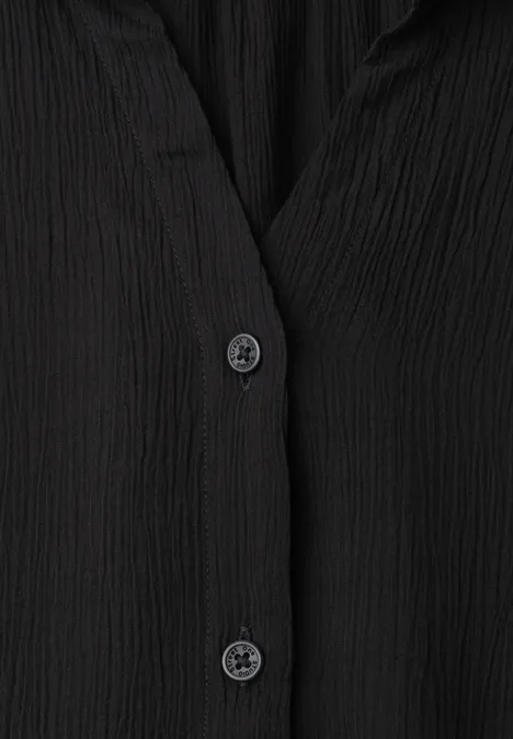 Schwarze Bluse aus geripptem Stoff mit zwei schwarzen Knöpfen.