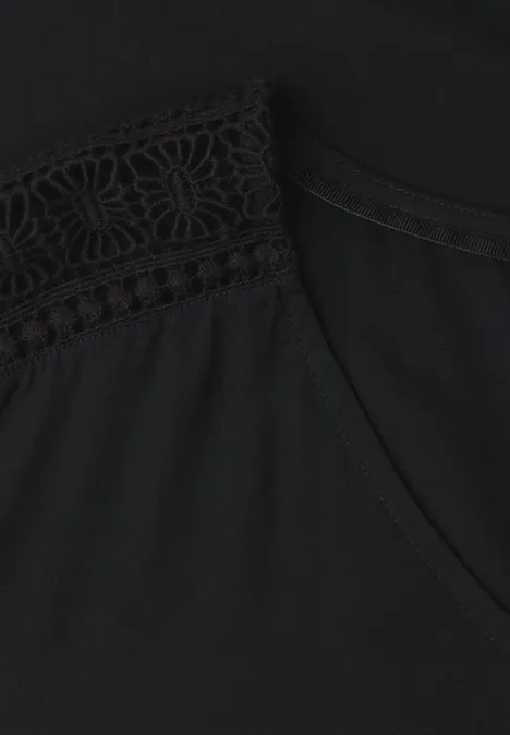 Schwarzes Oberteil mit zartem Spitzenbesatz am Schulterbereich.