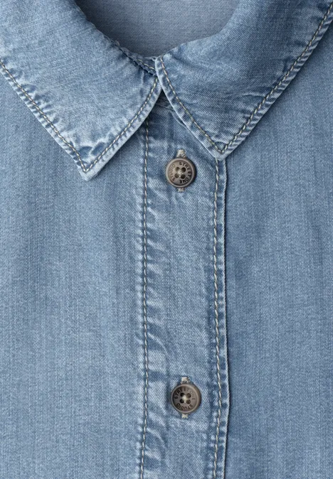 Hellblaues Jeanshemd, Knopfleiste und spitzer Kragen in Nahaufnahme.