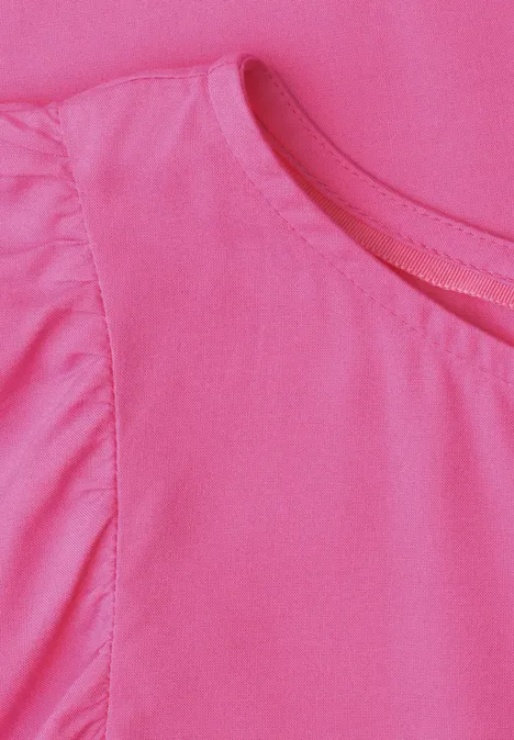 Un t-shirt rose avec un léger détail à volants le long de la couture d'épaule.