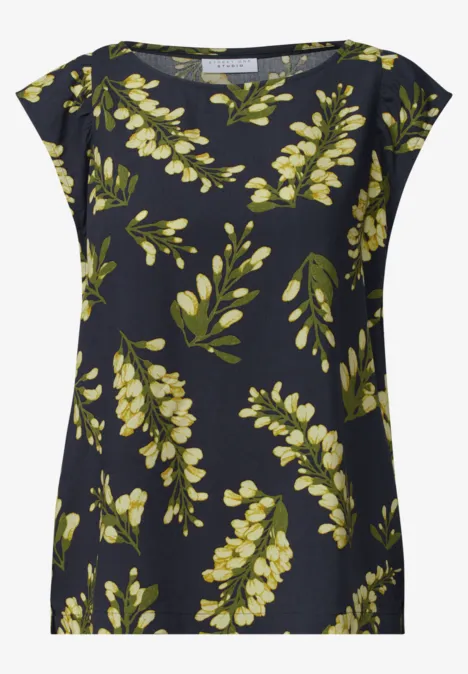 Donkerblauw damestop met losse pasvorm en geelgroen bladpatroon.