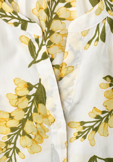 Close-up van een witte stof met geel-groen bloemenpatroon.