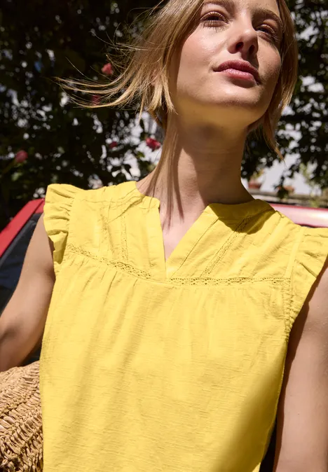 Blusenshirt mit Split Neck und Tape-Details snap yellow Person trägt gelbes, ärmelloses Oberteil mit Rüschen, hält geflochtenen Korb, Gesicht unscharf im Freien