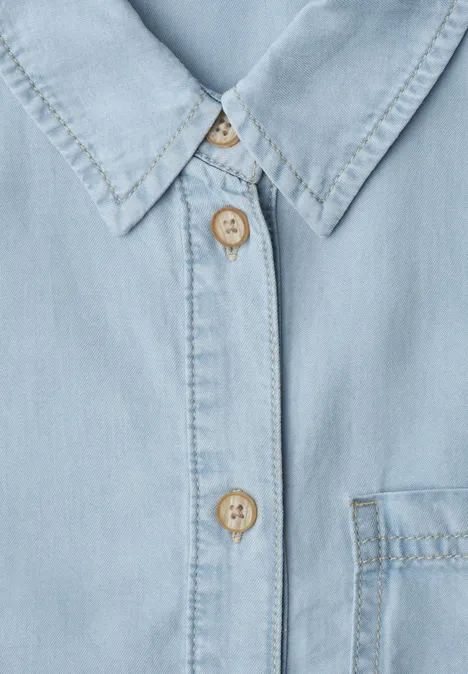 Kurzarm Hemdbluse aus Lyocell soft light blue wash Nahaufnahme eines hellblauen Jeanshemds mit Kragen, Brusttasche und Holzknöpfen.