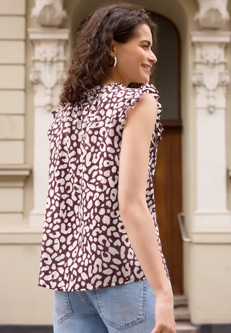 Blusentop mit V-Neck und Leo-Print vanilla sand Frau von hinten in Jeans und ärmellosem Oberteil mit Leopardenmuster vor einem Gebäude.