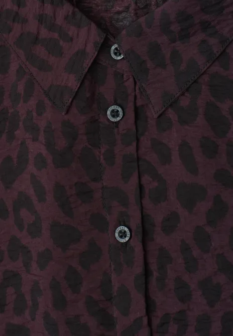 Nahaufnahme eines bordeauxfarbenen Hemds mit schwarzem Leopardenmuster und Knopfleiste.