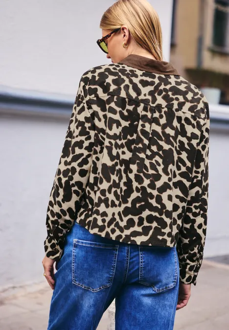Dame steht mit dem Rücken zur Kamera und trägt pink-schwarzen Leo-Pulli und Jeans