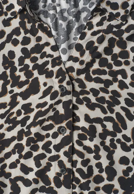 Close-up van een hemd met zwart-bruin luipaardprint op lichte stof en zichtbare knopen.