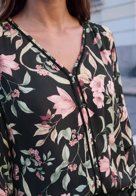 Schwarzes Oberteil mit rosa-weißen Blumenmustern und Knopfleiste im V-Ausschnitt.