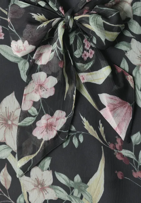 Schwarzes Stoffstück mit floraler Musterung und einem dekorativen Knoten aus Blüten und Blättern.