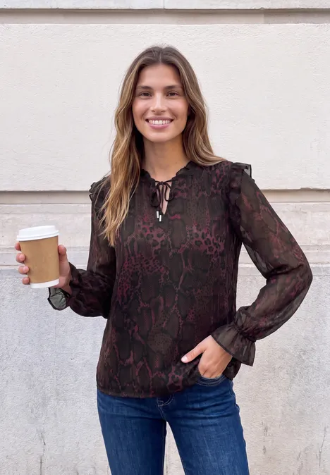 Langarm Tunika mit Rüschendetails russet red Eine lächelnde Frau in Bluse und Jeans hält einen Pappbecher vor einer hellen Wand.