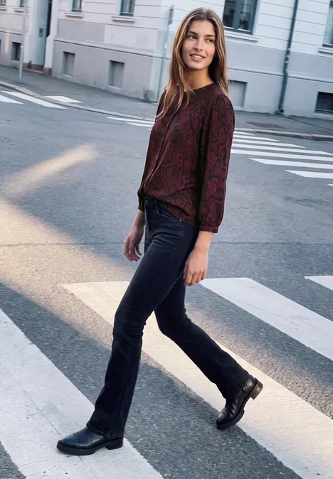 3/4-Arm Tunika mit Rundhals und Snake-Print russet red Eine junge Frau in dunkelrotem Pullover, Jeans und Boots, die entspannt über einen Zebrastreifen geht.