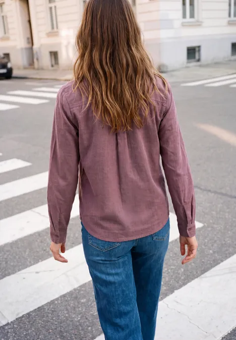 Hemdbluse aus Cord mit Herzdetail hazy rose Person mit kastanienbraunem Hemd und blauen Jeans überquert eine Straße am Zebrastreifen