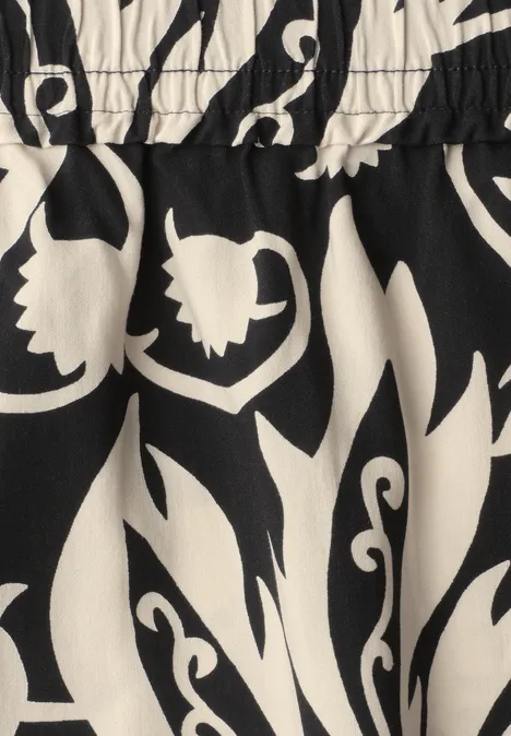 Midi-Rock mit Volants und Print Black Schwarzes Kleidungsstück mit elastischem Bund und weißem Blumenblattmuster.