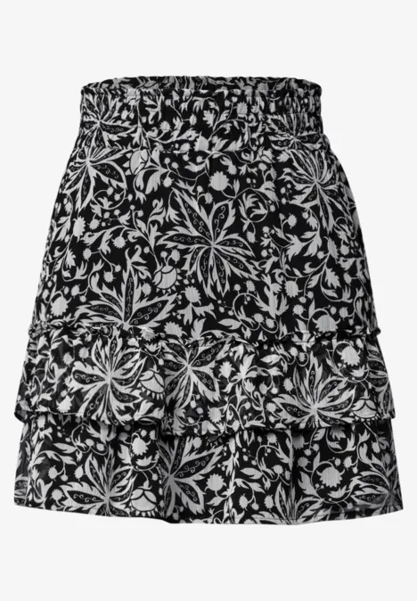Knielange chiffonrok met volants Black Kort zwart rokje met dubbele laag en wit bloemenpatroon.