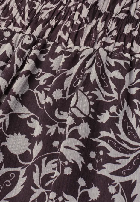 Knielange chiffonrok met volants very berry Close-up van zwart-witte bloemenprint op geplooide stof.