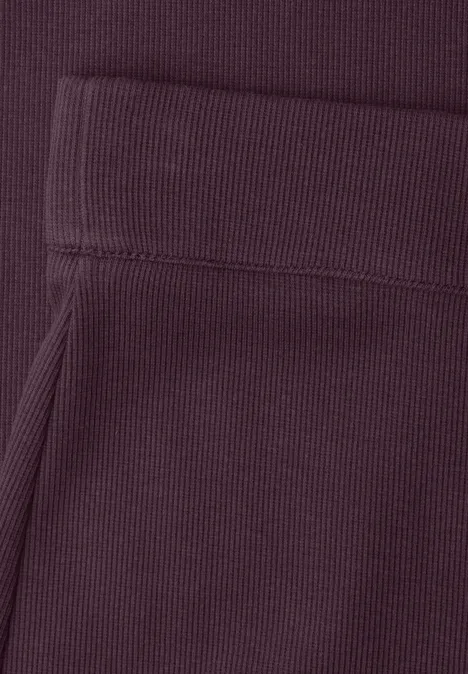 Close-up van een donkerpaars kledingstuk met geribbelde boord en zak.