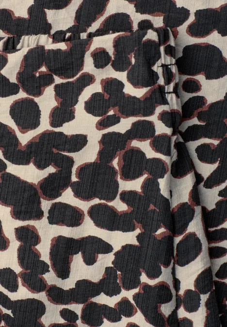 Beige Stoff mit schwarzem Leopardenmuster und dezenten roten Umrandungen.