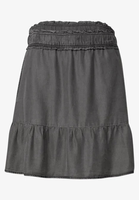 Korte donkergrijze denim rok met elastische taille en subtiele franje onderaan.