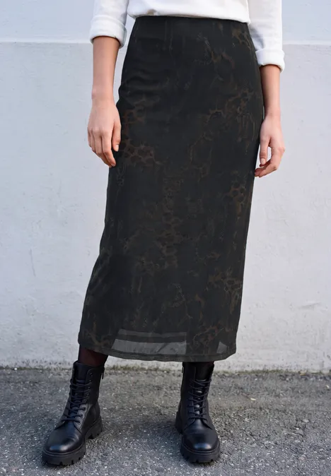 Zwarte, licht transparante midirok met subtiel bloemenpatroon, gecombineerd met zwarte veterboots.