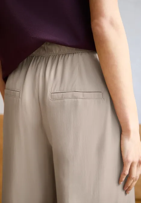Wide Leg Culotte im Loose Fit quiet ivory Eine Person trägt beigefarbene, leichte Hose mit angedeuteten Gesäßtaschen, Hand am Oberschenkel.
