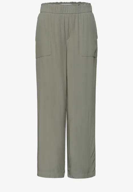 Locker sitzende, hellgrau-grüne Hose mit elastischem Bund und seitlichen Taschen.