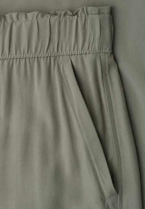 Nahaufnahme von grünlichen Hosen mit Gummibund und Tasche.