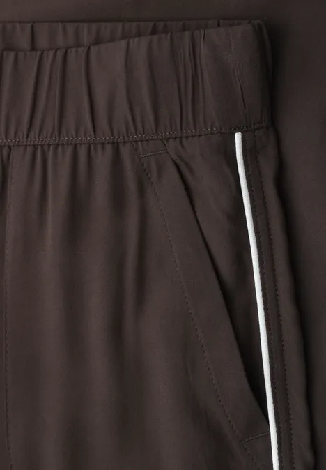 Braune Sporthose mit elastischem Bund und seitlicher Tasche mit weißem Streifen.