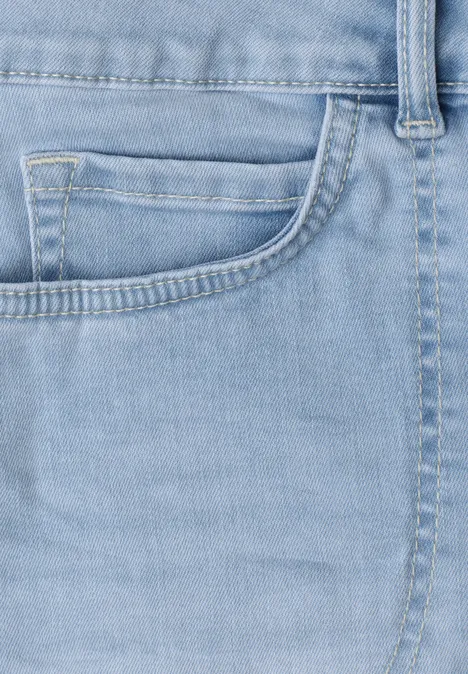 Nahaufnahme einer hellblauen Jeansvorderseite mit Münztasche und Nahtdetails.