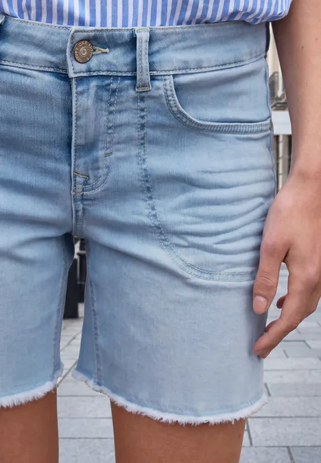 Helle Jeansshorts mit ausgefransten Säumen und sichtbarer Knopfleiste, seitliche Tasche und Handansicht.
