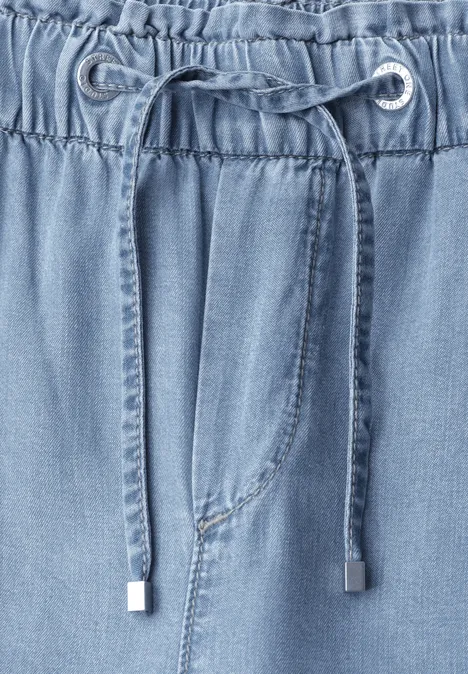 Nahaufnahme eines hellblauen Jeanshosenbunds mit elastischem Tunnelzug und Kordel