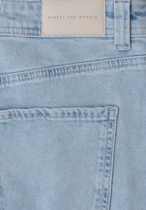 Close-up van lichtblauwe spijkerbroek met achterzak en label in de taille.