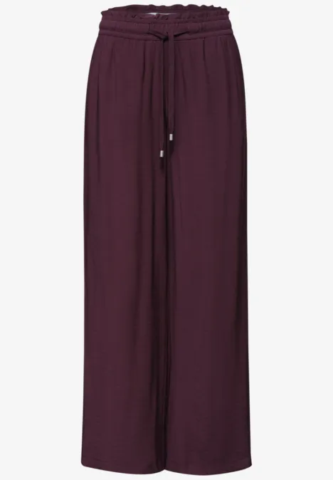 Wijde, vloeiende broek in auberginekleurige stof met trekkoord in de taille.