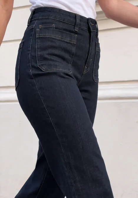 Mid Waist Wide Leg Jeans im Loose Fit rinsed blue washed Nahaufnahme einer Person in hochgeschnittener, dunkelblauer Jeanshose.