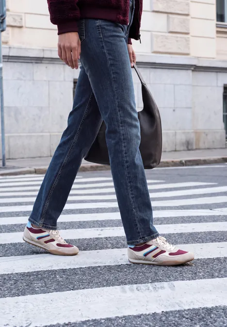 Mid Waist Straight Leg Jeans im Casual Fit dark blue random washed Person in Jeans und Sneakern überquert einen Zebrastreifen auf der Straße.
