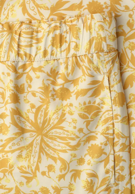 Geel-wit stoffen patroon met bloemenmotief.