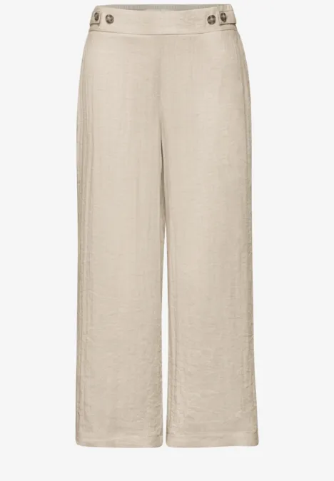Beige linnen broek met wijd model, hoge taille en knoopdetail aan de tailleband.