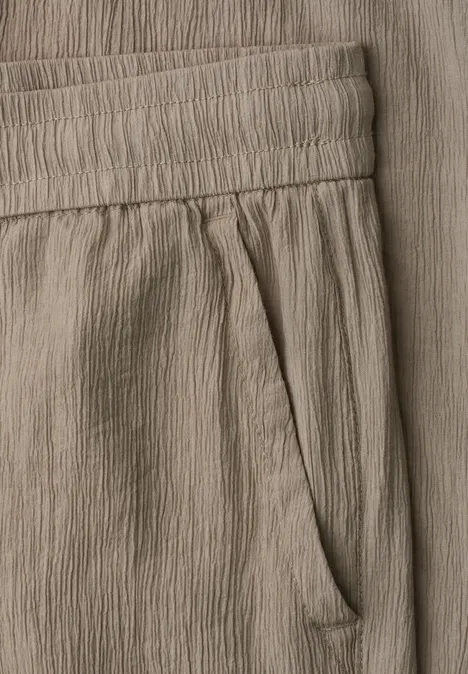 Straight Leg Hose mit Crinkle Struktur dark stone sand Detailaufnahme einer beigen Crinkle-Stoffhose mit elastischem Bund und seitlicher Tasche