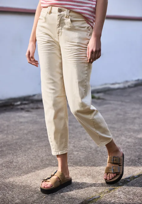 Iemand staat buiten in lichtgekleurde broek tot de enkels en bruine sandalen met gespen.