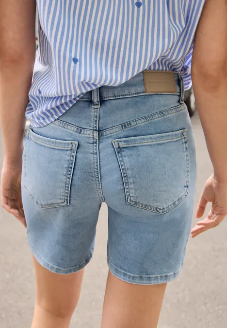 Straight Leg Jeansshorts im Casual Fit Light Blue Random washed Person von hinten in hellblauen Jeans-Shorts und gestreiftem Hemd auf hellem Untergrund.