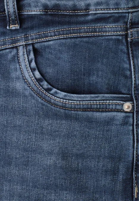 Close-up van een donkerblauwe spijkerbroek met zichtbare zak en stiksels.